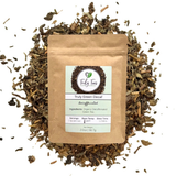 Tea package labeled 'Truly Green Decaf' surrounded by loose tea leaves on a white background