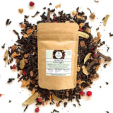 Vanilla chai tea package surrounded by loose tea leaves on a white background